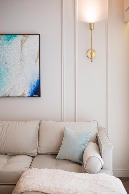 Sofá esquinero tapizado en tono beige claro, con almohadones a juego, ubicado en un living luminoso de estilo moderno.