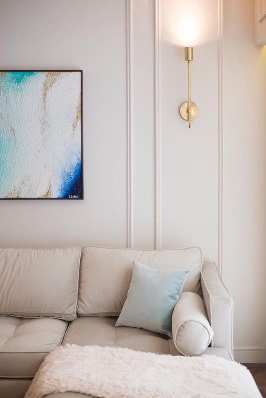 Sofá esquinero tapizado en tono beige claro, con almohadones a juego, ubicado en un living luminoso de estilo moderno.
