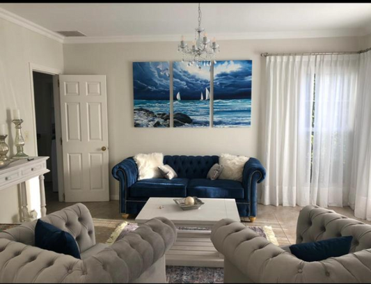 Juego de sillones con tapizado capitoné en tonos azul marino y gris, de diseño elegante y clásico, ubicados en un living luminoso con decoración sofisticada