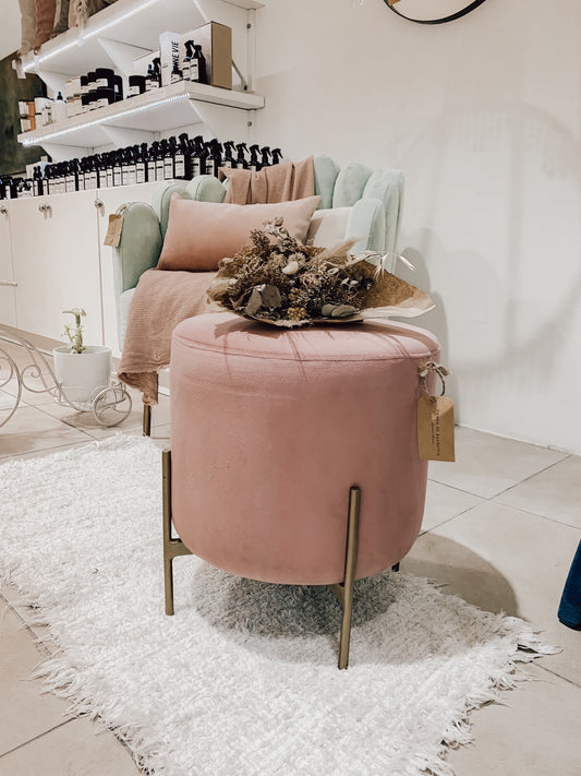 Puff redondo tapizado con patas metálicas doradas. Diseño moderno y sofisticado, ideal como acento decorativo en cualquier ambiente.