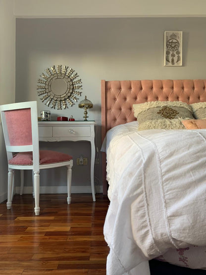 Respaldo alto tapizado en terciopelo rosa suave con diseño capitoné de botones, que aporta un toque elegante y acogedor al dormitorio