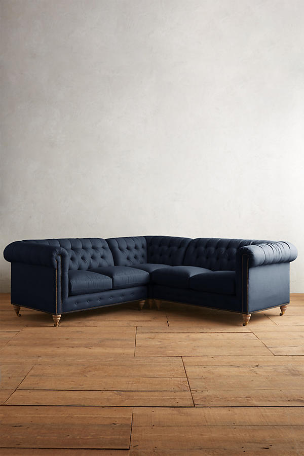 Sillón esquinero estilo Chesterfield en pana azul con capitoné, brazos curvos y patas altas. Clásico inglés con personalidad.