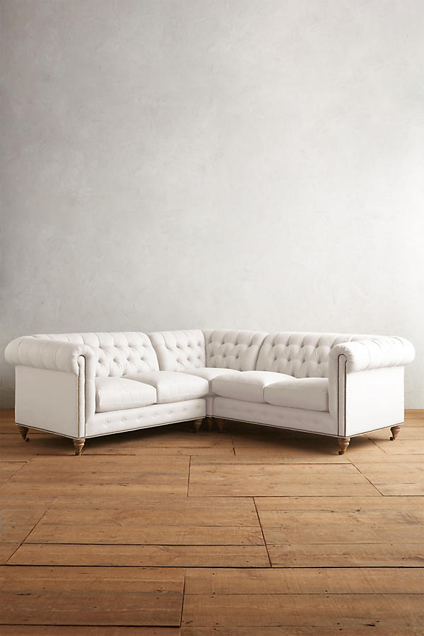 Sillón esquinero estilo Chesterfield en pana blanco con capitoné, brazos curvos y patas altas. Clásico inglés con personalidad.