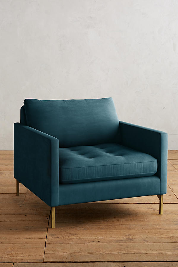 Sillón individual moderno en color azul con respaldo y asiento acolchados, apoyabrazos rectos y patas metálicas finas en dorado, sobre fondo blanco.