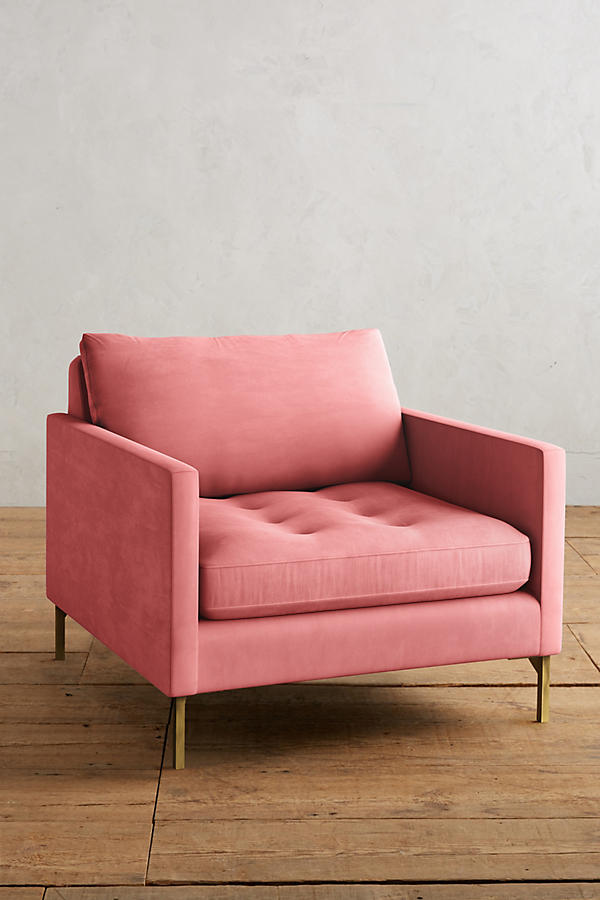 Sillón individual moderno en color rosa con respaldo y asiento acolchados, apoyabrazos rectos y patas metálicas finas en dorado, sobre fondo blanco.