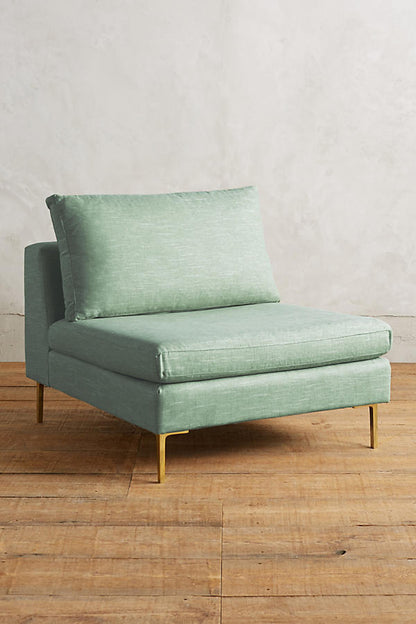 Módulo de sillón sin apoyabrazos en color verde claro, con respaldo alto y almohadón mullido, patas metálicas delgadas en tono dorado, sobre fondo blanco.