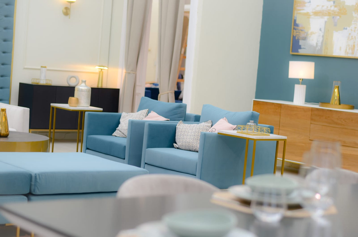 Sillón individual moderno en color celeste con respaldo y asiento acolchados, apoyabrazos rectos y patas metálicas finas en dorado