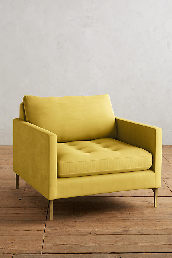 Sillón individual moderno en color amarillo con respaldo y asiento acolchados, apoyabrazos rectos y patas metálicas finas en dorado, sobre fondo blanco.