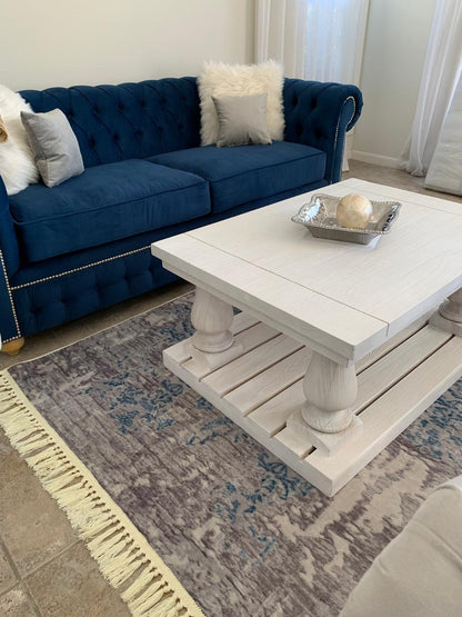 Juego de sillones con tapizado capitoné en tonos azul marino y gris, de diseño elegante y clásico, ubicados en un living luminoso con decoración sofisticada