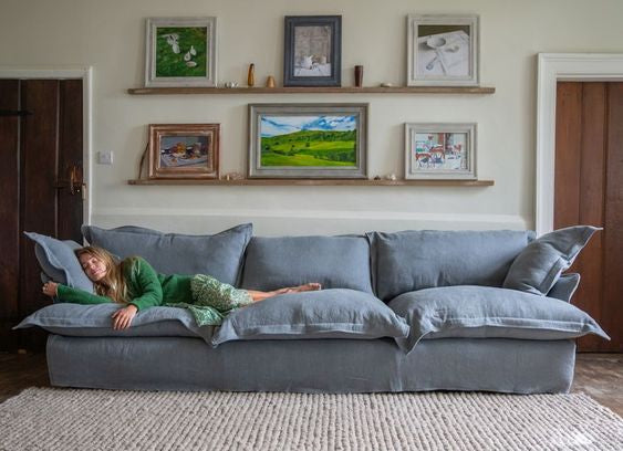 Sofá Comfy enfundado, con respaldo y apoyabrazos integrados, amplios cojines extra mullidos en asiento y respaldo, líneas suaves y estructura de base baja, presentado sobre fondo blanco, ideal para livings contemporáneos o espacios de descanso que buscan máxima comodidad y estilo relajado.