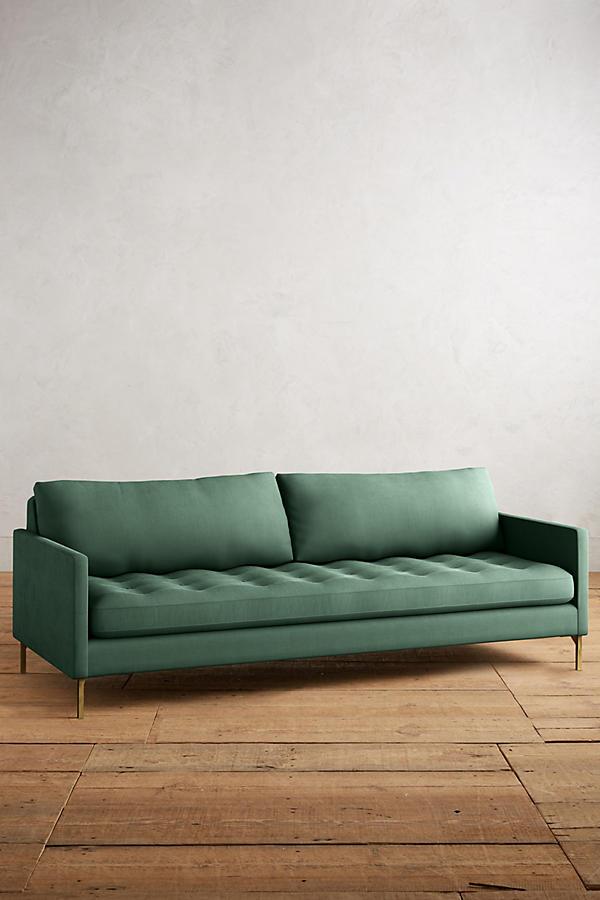 Sillón Ristretto de dos cuerpos con respaldo de almohadones sueltos, asiento tapizado capitoné y patas finas metálicas doradas. Diseño moderno y elegante con detalles clásicos.