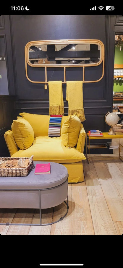 Sillón individual tapizado en amarillo, de estilo desenfundable, con asiento y respaldo mullidos, acompañado por dos cojines laterales sueltos que aportan volumen y comodidad.
