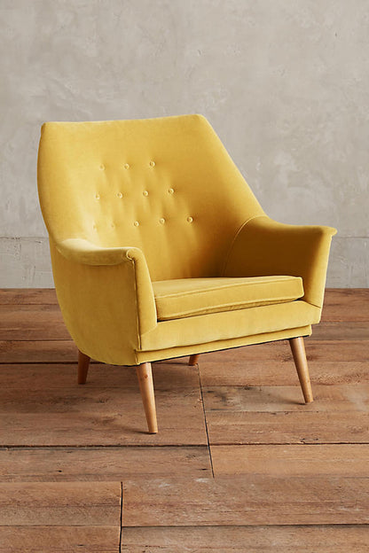 Sillón individual tapizado en amarillo, de diseño retro con respaldo inclinado, asiento acolchado y patas de madera inclinadas estilo escandinavo.