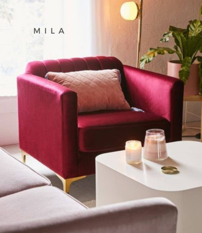 Sillón de un cuerpo tapizado en bordo, con respaldo recto acanalado, apoyabrazos rectangulares y base baja con patas doradas.