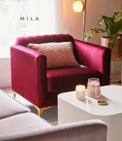 Sillón de un cuerpo tapizado en bordo, con respaldo recto acanalado, apoyabrazos rectangulares y base baja con patas doradas.