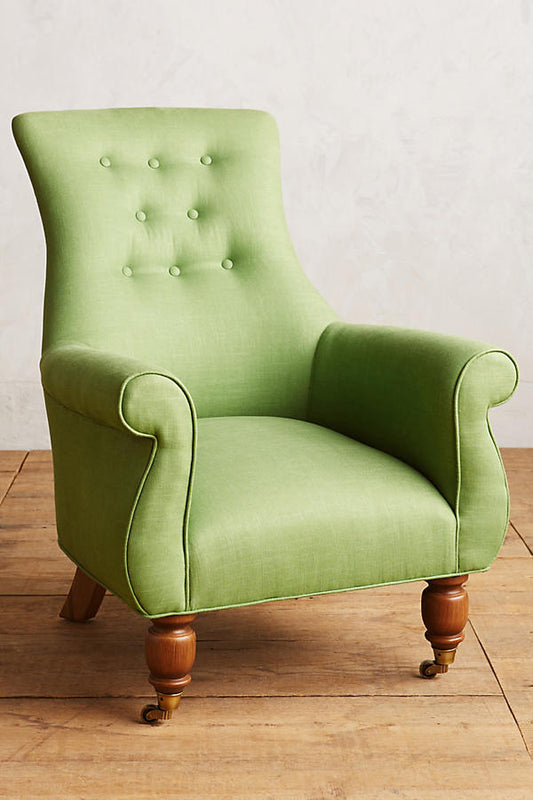 Sillón individual estilo clásico tapizado en verde, con respaldo alto capitoné, apoyabrazos curvos y patas torneadas de madera.