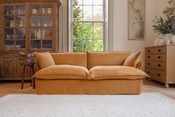 Sofá Comfy enfundado, con respaldo y apoyabrazos integrados, amplios cojines extra mullidos en asiento y respaldo, líneas suaves y estructura de base baja, presentado sobre fondo blanco, ideal para livings contemporáneos o espacios de descanso que buscan máxima comodidad y estilo relajado.