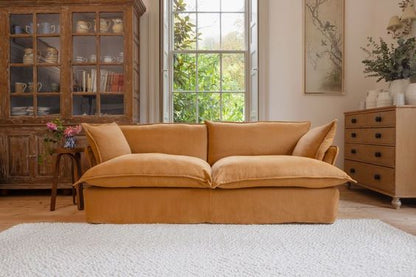 Sofá Comfy enfundado, con respaldo y apoyabrazos integrados, amplios cojines extra mullidos en asiento y respaldo, líneas suaves y estructura de base baja, presentado sobre fondo blanco, ideal para livings contemporáneos o espacios de descanso que buscan máxima comodidad y estilo relajado.