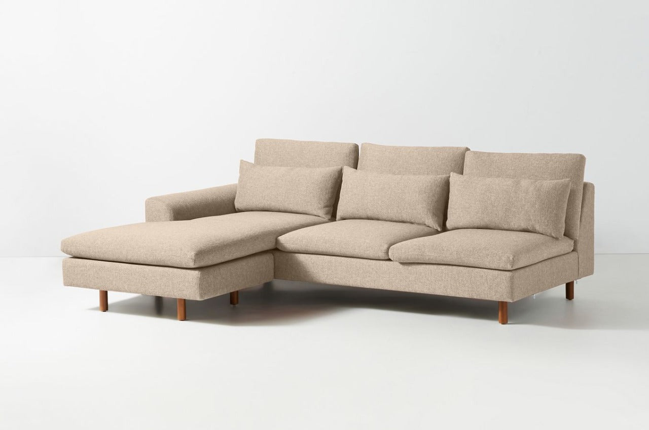 Sillón esquinero moderno en pana crema, respaldo alto y estructura sólida con patas de madera natural.