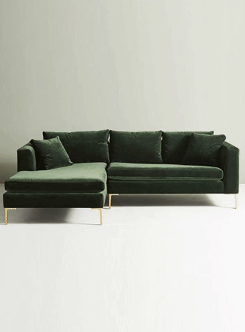 Sillón esquinero moderno en verde con patas doradas, líneas limpias y almohadones sueltos. Estilo nórdico con toque glam.