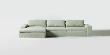 Sillón esquinero tapizado en gris, diseño lineal con base baja y almohadones grandes. Estética minimalista y fresca.