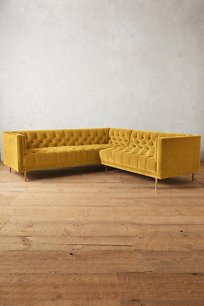 Sillón esquinero clásico en amarillo con respaldo capitoné profundo, apoyabrazos rectos y patas finas de madera. Diseño elegante y sofisticado.