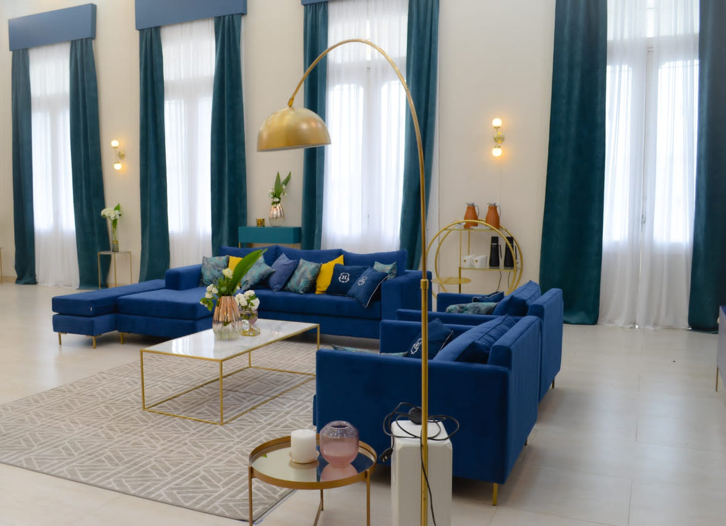 Sillón esquinero moderno en azul con patas doradas, líneas limpias y almohadones sueltos. Estilo nórdico con toque glam.