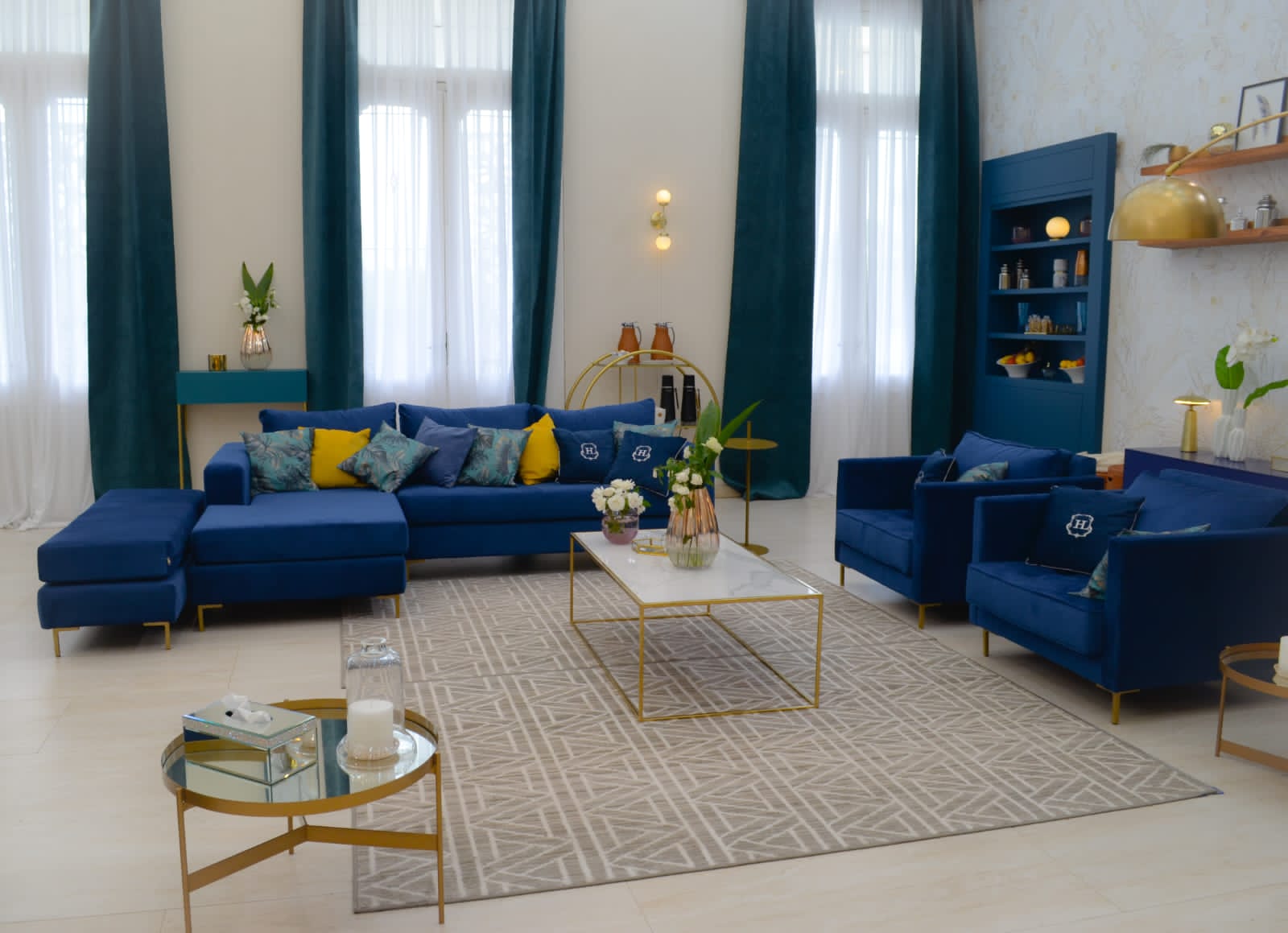 Sillón esquinero moderno en azul con patas doradas, líneas limpias y almohadones sueltos. Estilo nórdico con toque glam.
