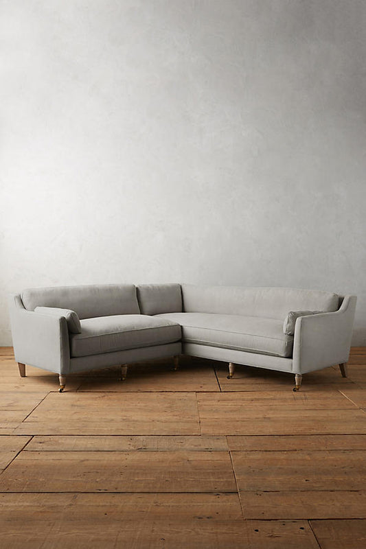 Sillón esquinero de diseño liviano en gris, estructura baja y líneas minimalistas. Ideal para ambientes femeninos y luminosos.