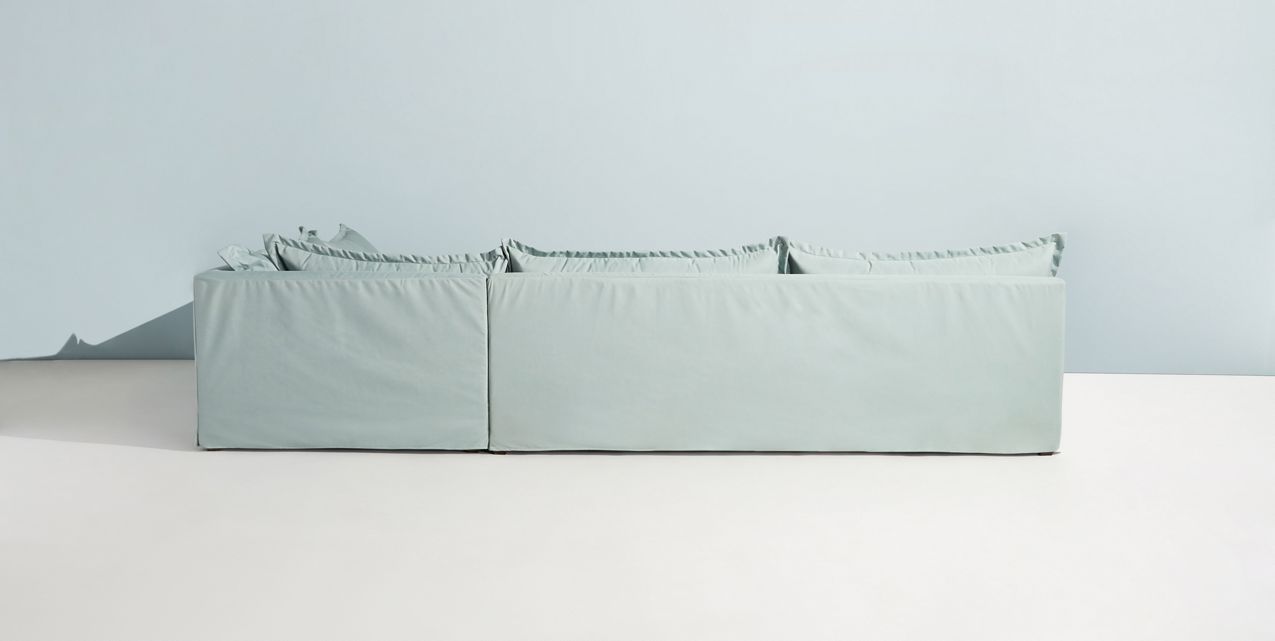 Sillón esquinero grande en lino gris claro con respaldo bajo, almohadones sueltos y chaise longue. Diseño descontracturado y moderno.