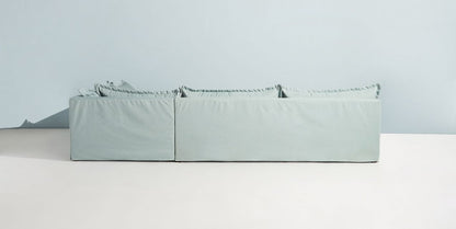 Sillón esquinero grande en lino gris claro con respaldo bajo, almohadones sueltos y chaise longue. Diseño descontracturado y moderno.