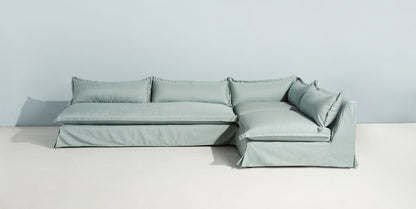 Sillón esquinero grande en lino gris claro con respaldo bajo, almohadones sueltos y chaise longue. Diseño descontracturado y moderno.