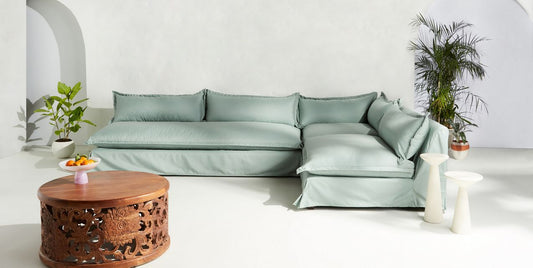 Sillón esquinero grande en lino gris claro con respaldo bajo, almohadones sueltos y chaise longue. Diseño descontracturado y moderno.