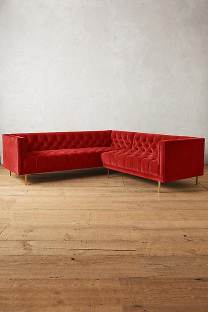 Sillón esquinero clásico en rojo con respaldo capitoné profundo, apoyabrazos rectos y patas finas de madera. Diseño elegante y sofisticado.