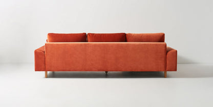 Sillón esquinero en tono rojo con líneas rectas, patas de madera claras y apoyabrazos rectangulares. Ideal para espacios cálidos.