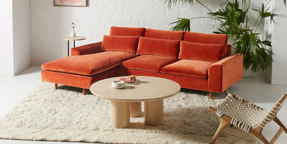 Sillón esquinero en tono rojo con líneas rectas, patas de madera claras y apoyabrazos rectangulares. Ideal para espacios cálidos.