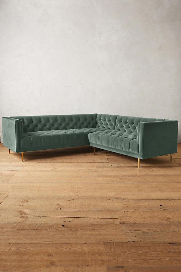 Sillón esquinero clásico en verde con respaldo capitoné profundo, apoyabrazos rectos y patas finas de madera. Diseño elegante y sofisticado.
