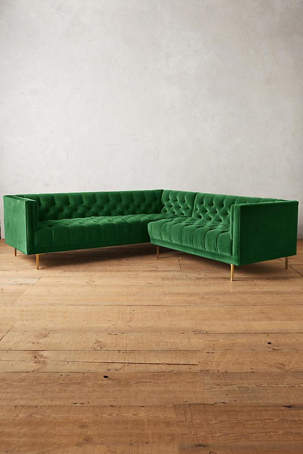 Sillón esquinero clásico en verde con respaldo capitoné profundo, apoyabrazos rectos y patas finas de madera. Diseño elegante y sofisticado.