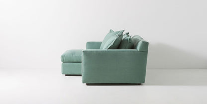 Sillón esquinero verde con apoyabrazos rectos, estructura firme y respaldo mullido. Perfecto para livings amplios.