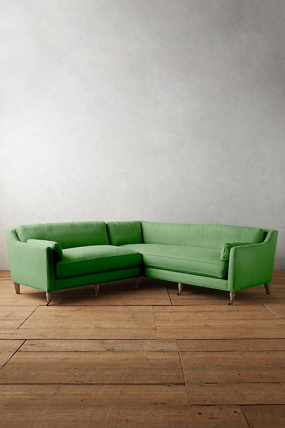 Sillón esquinero de diseño liviano en verde, estructura baja y líneas minimalistas. Ideal para ambientes femeninos y luminosos.