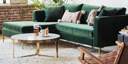 Sillón esquinero moderno en verde con patas doradas, líneas limpias y almohadones sueltos. Estilo nórdico con toque glam.