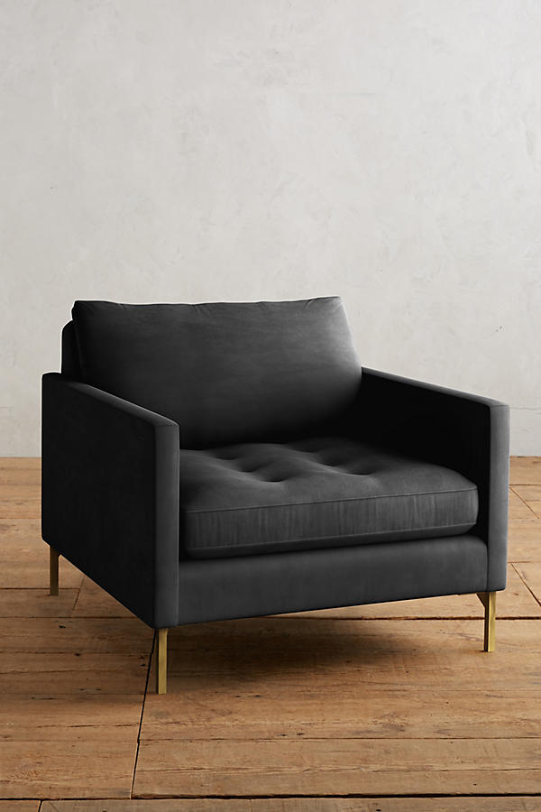 Sillón individual moderno en color gris con respaldo y asiento acolchados, apoyabrazos rectos y patas metálicas finas en dorado, sobre fondo blanco.