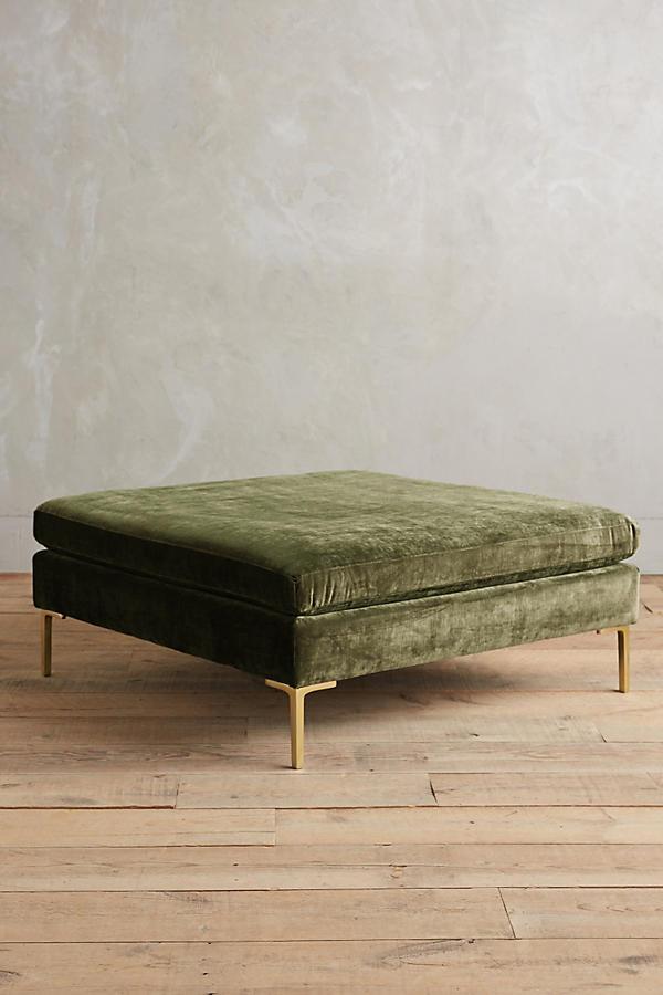 Banqueta Pie de Cama Otomana verde con patas metálicas doradas, sobre piso de madera