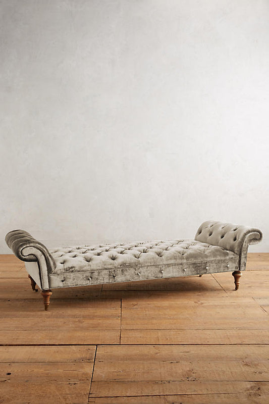 Banqueta Pie de Cama Chesterfield beige con capitoné y brazos enrollados, sobre piso de madera
