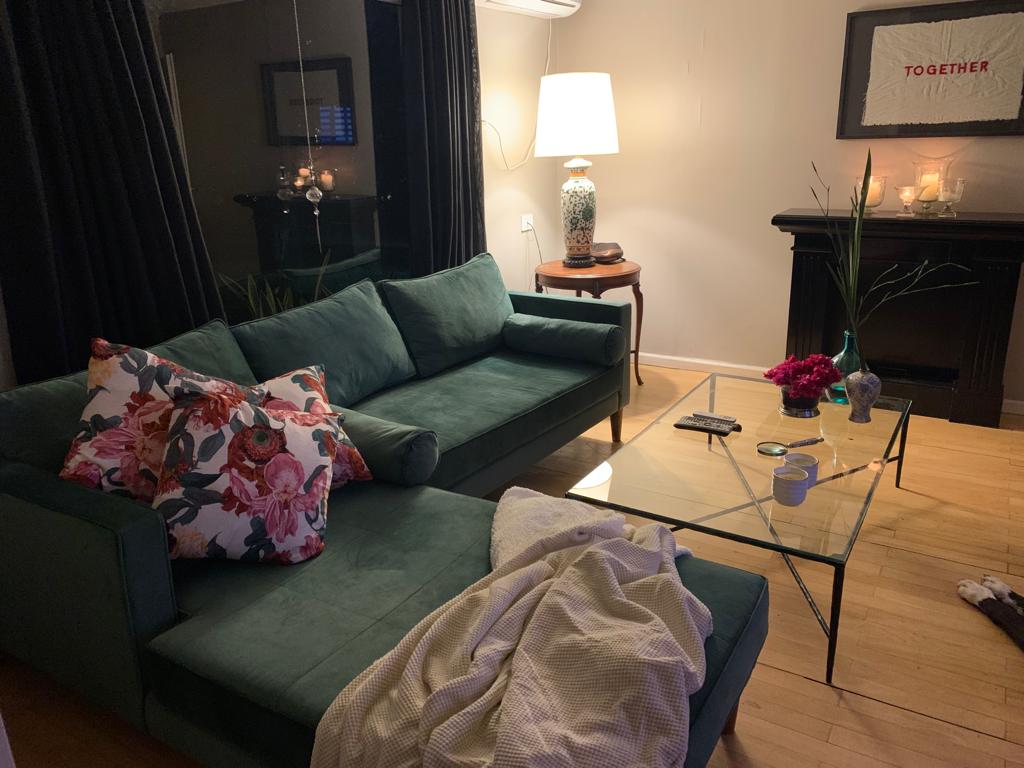 Esquinero Bambú verde de Patri desde el chaise, con lámpara de cerámica, mesa de luz de madera y chimenea negra al fondo