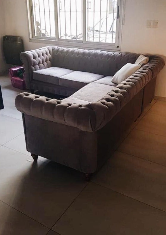 Sillón Esquinero Chesterfield en L en terciopelo topo, con capitoné y patas torneadas, en el living de Guillermina