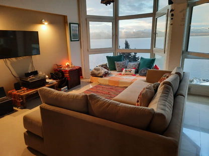 Esquinero Elton beige de espaldas, mirando al lago al atardecer, en el living de Maia en Bariloche