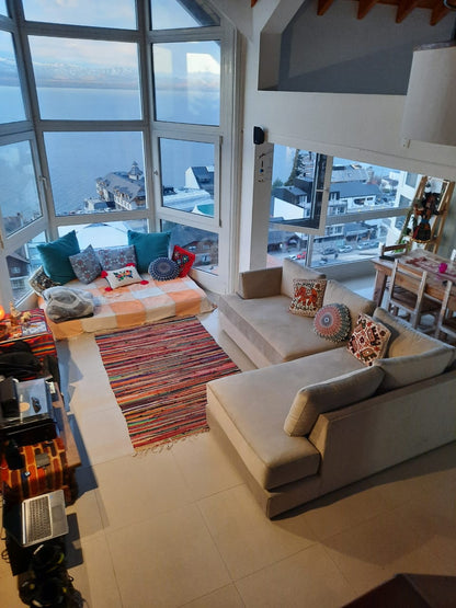 Esquinero Elton beige con chaise frente a los ventanales con vista al lago, en la casa de Maia en Bariloche