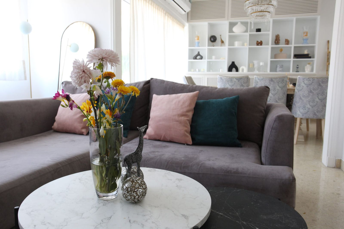 Esquinero Elton gris malva con almohadones rosa y verde petróleo, en el living de Naza Winograd