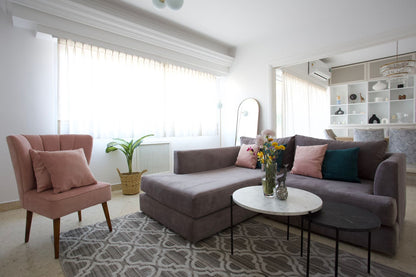 Esquinero Elton gris malva con chaise y Sillón Matero Alpes rosa, con mesas ratonas de mármol, en el living de Naza Winograd